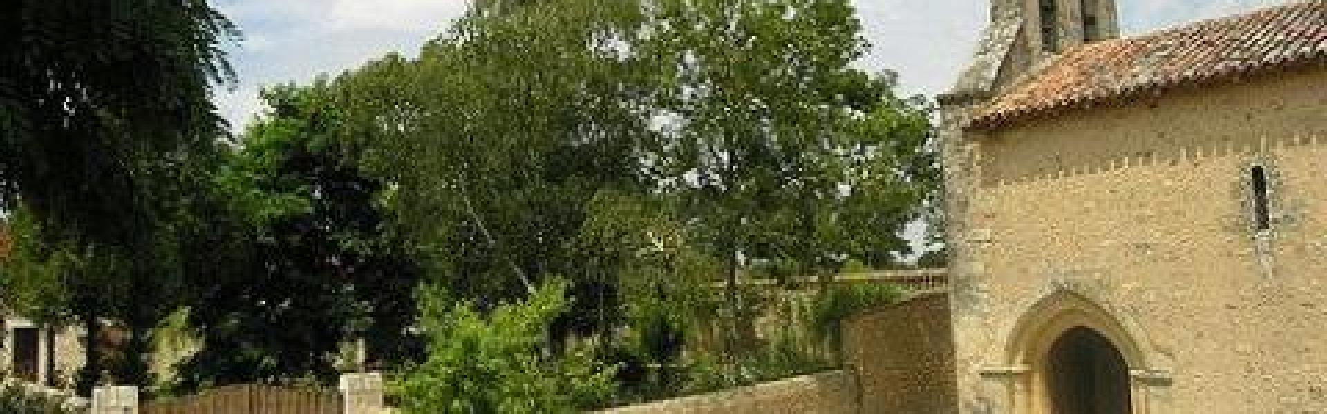 Une vue en journée de l'entrée de la Chapelle de Cramard avec de la verdure et un ciel bleu et nuageux.
