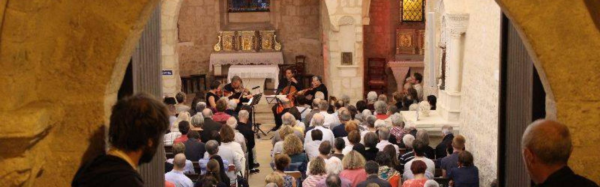 Une foule dans une église écoute un quatuor à cordes à Quinçay