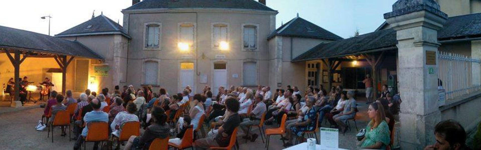 Une photo en fin de journée de la cour de la Mairie de Frozes. Un public très nombreux écoute les musiciens.