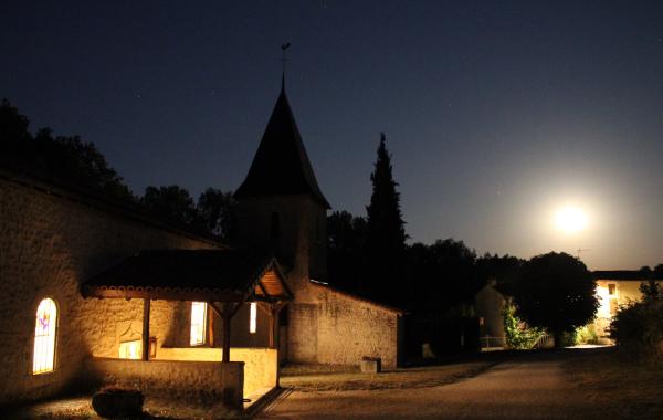 L'église de Quinçay vue de nuit en pose longue, la lune ressemble au soleil et on voit de la lumière sortir de l'Eglise