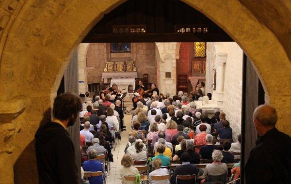 Une foule dans une église écoute un quatuor à cordes à Quinçay