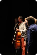 une photo en clair obscur de musiciens saluant le public