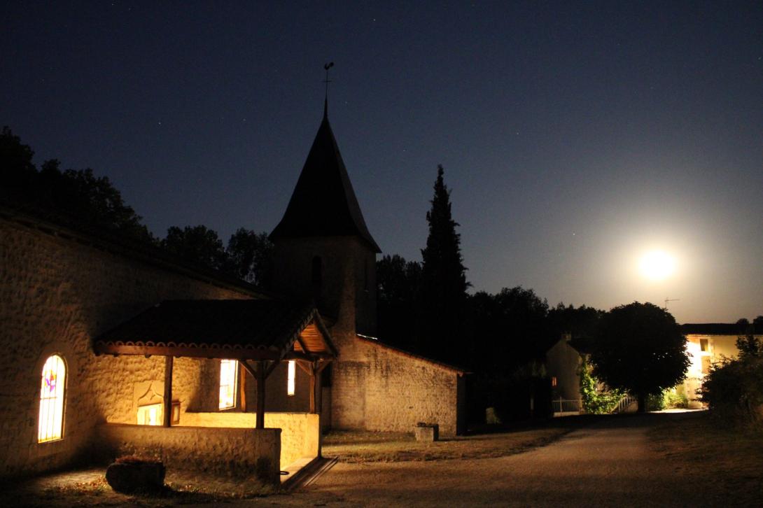 L'église de Quinçay vue de nuit en pose longue, la lune ressemble au soleil et on voit de la lumière sortir de l'Eglise